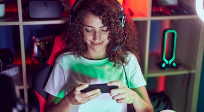 1_jovem_bela_mulher_hispanica_streamer_jogando_videogame_usando_smartphone_na_sala_de_jogos-34707370