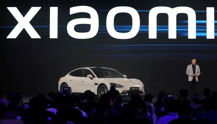 Fundador e CEO da Xiaomi, Lei Jun, ao lado do primeiro veículo elétrico da Xiaomi, em um evento...