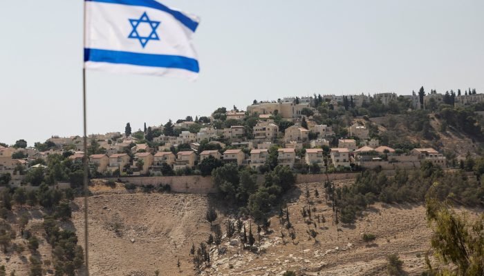 Bandeira israelense na Cisjordânia ocupada por Israel com assentamento Maale Adumim ao fundo 14/...