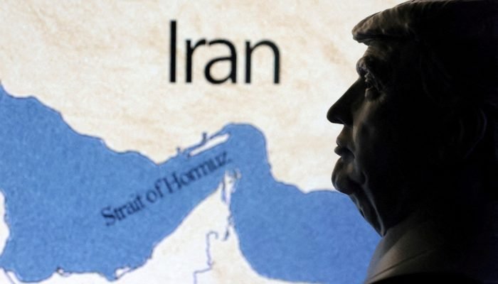 Um mapa mostrando o Estreito de Ormuz e o Irã aparece ao fundo de uma miniatura em 3D do preside...