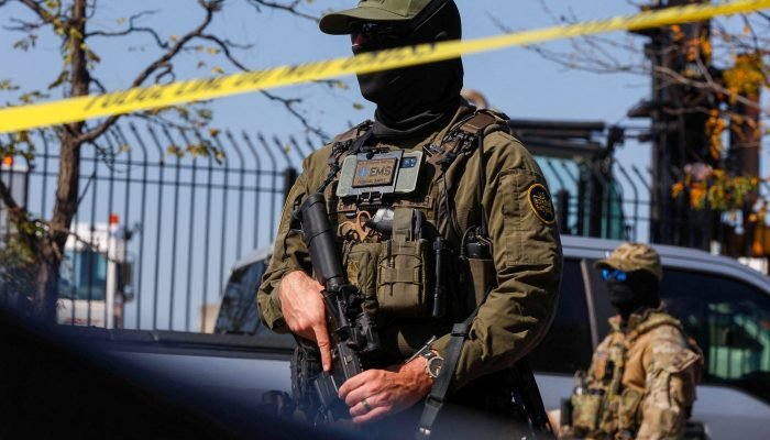 Um agente da Patrulha da Fronteira dos EUA permanece atrás da fita de isolamento durante um conf...