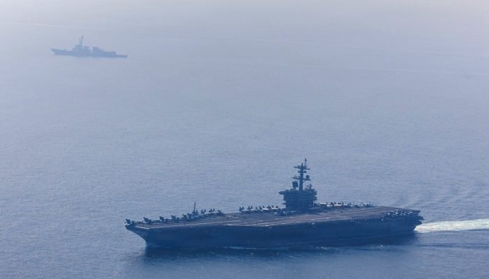 O porta-aviões USS Abraham Lincoln, da Marinha dos EUA, da classe Nimitz, e o destróier lança-...