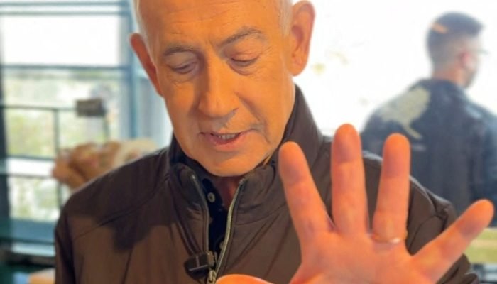 O primeiro-ministro israelense, Benjamin Netanyahu, mostra a mão enquanto discursa em um café, ...