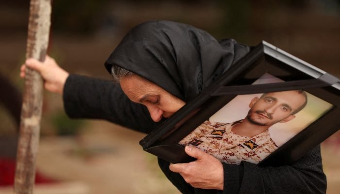 16 de março de 2026 - Marzia Rezaei parada em um cemitério de Teerã ao lado do túmulo de seu ...