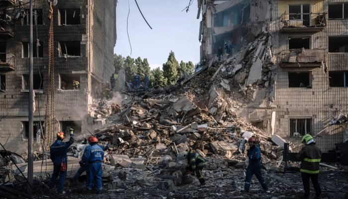 Equipes de resgate buscam vítimas sob os escombros após um ataque aéreo a um prédio residenci...