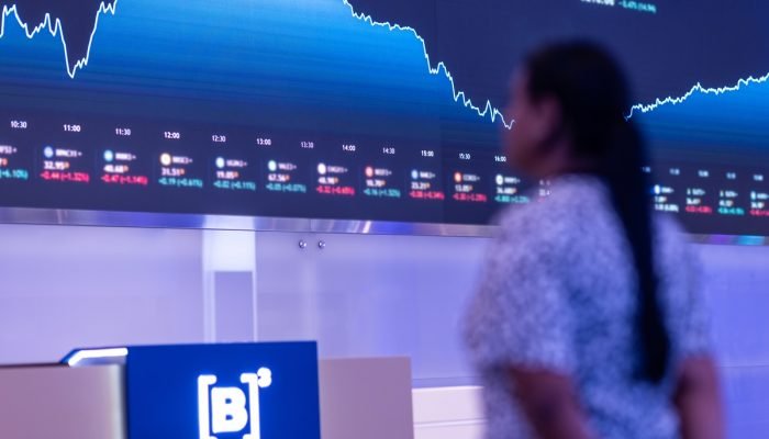 Mulher observa o painel de cotações da B3 (Imagem: Divulgação B3)