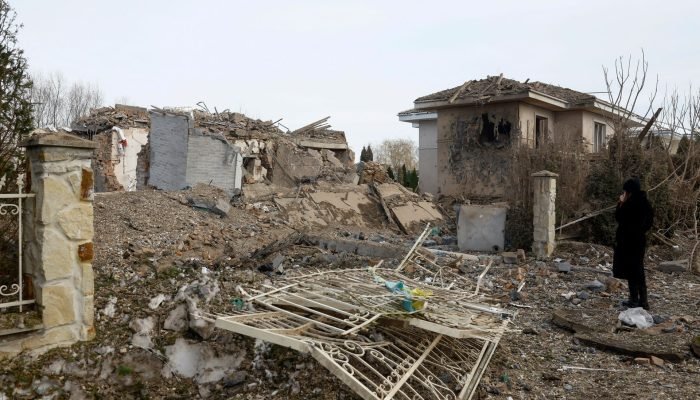 Mulher observa danos em casa após ataque de míssil russo na região da capital Kiev - 22/02/202...