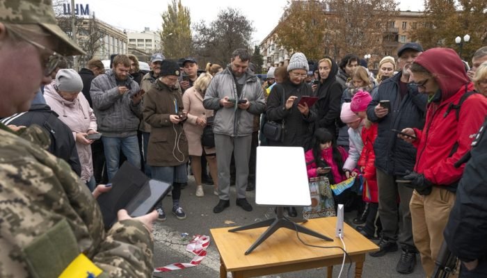 Ucranianos fazem fila para acessar internet via satélite em uma conexão Starlink em Kherson, em...