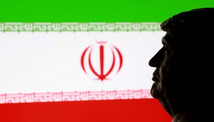 Miniatura impressa em 3D do presidente dos EUA, Donald Trump, com a bandeira iraniana ao fundo - ...